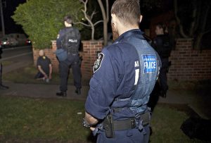 An Australian Federal Police officer, right, and a New South Wales policeman detain a person during a raid on a house in Sydney.