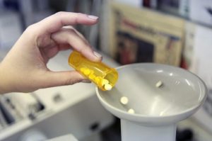 A pharmacy employee dumps pills into a pill counting machine as she fills a prescription while working at a pharmacy in New York